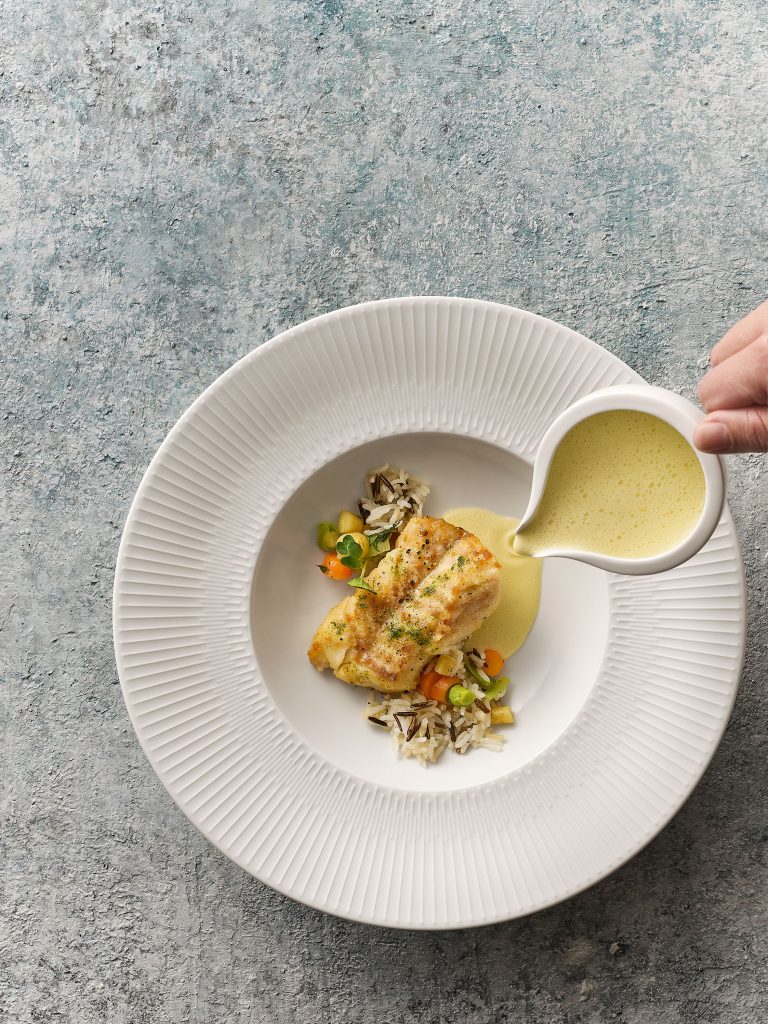 Woman pours sauce into vegan porcelain plate