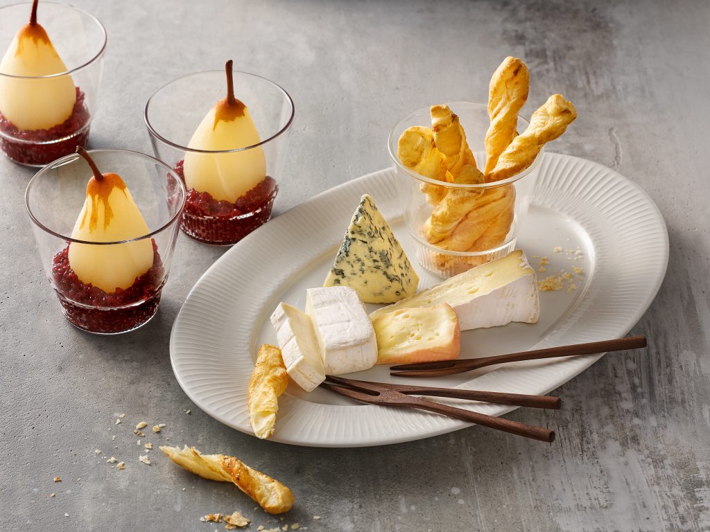 Cheese platter arranged on vegan porcelain. Cheese variations, red wine pears, 